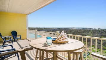 A balcony with a table, chairs, and a view of the ocean.