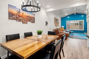A modern living room with a dining area, featuring a wooden dining table, leather sofas, and a blue accent wall. - Wild Wild West Walk To Old Town 3 Shared Pools (Scottsdale)