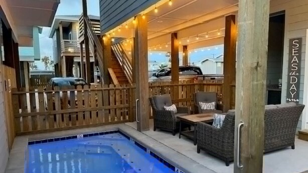 A pool area with a wooden deck, outdoor seating, and a sign reading 'SEASDAY'. - One Click Away Private Pool EV Charger Beach Toys (Port Aransas)