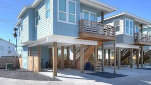 A two-story beachfront house with a balcony and a covered outdoor area. - One Click Away Private Pool EV Charger Beach Toys (Port Aransas)