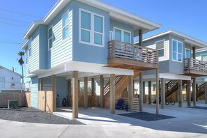 Ein zweigeschossiges Strandhaus mit Balkon und überdachter Terrasse.