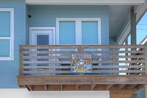 A balcony with a wooden railing and a sign that reads 'ON CLICK AWAY PORT ARANSAS, TEXAS'. - One Click Away Private Pool EV Charger Beach Toys (Port Aransas)