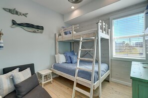 Ein Schlafraum mit Etagenbett, kleinem Tisch und einer Couch.