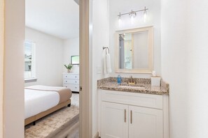 A bedroom with a bed, a nightstand, and a dresser. - 30A Golf Cart Arcade Resort-style Pool (Santa Rosa Beach)