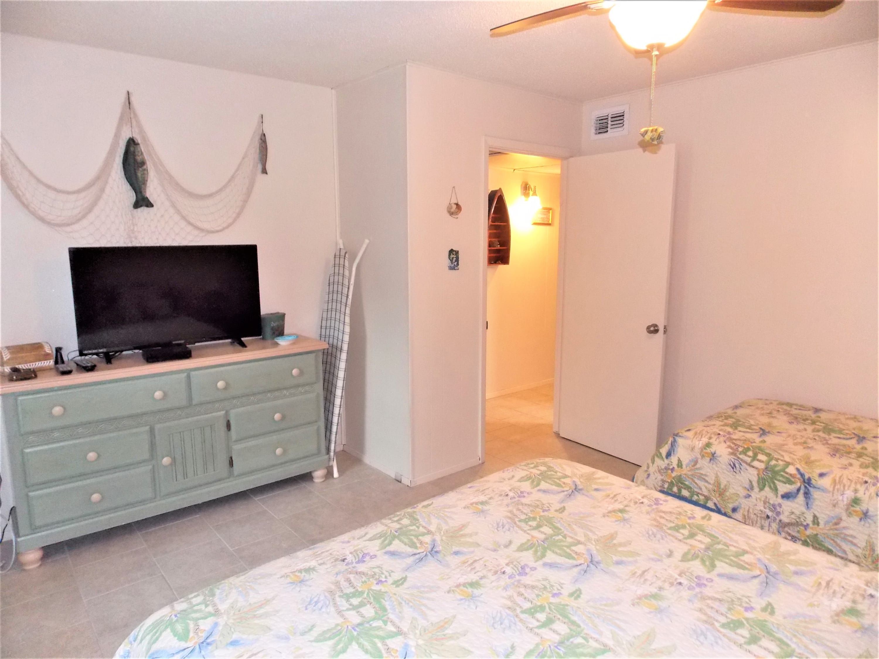 A bedroom with a bed, a dresser, a television, and a ceiling fan.