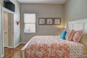 A bedroom with a bed, a window, and three framed pictures on the wall. - Happy Harbor 2 Resort Style Pools Playground (Port Aransas)