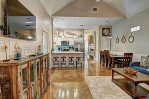 A spacious living area with a kitchen, dining table, and bar stools. - Happy Harbor 2 Resort Style Pools Playground (Port Aransas)
