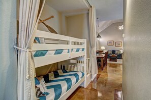 A bunk bed with white and blue bedding, a wooden ladder, and a curtain. - Happy Harbor 2 Resort Style Pools Playground (Port Aransas)
