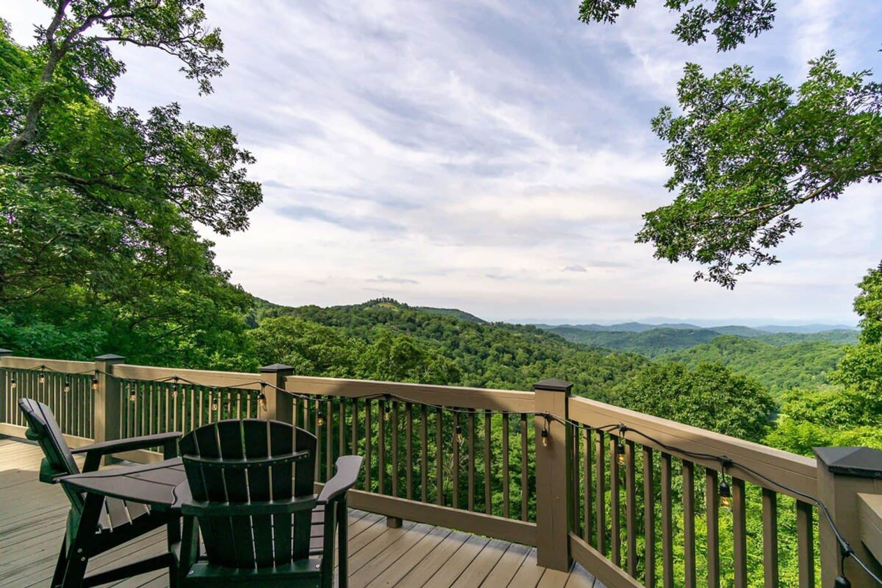 A deck with a view of a forested landscape.