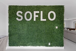 Eine Wand mit dem Schriftzug 'SOFLO' in großen Buchstaben, umgeben von einer grünen, grasartigen Struktur.