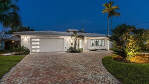 A two-story house with a brick driveway, a garage, and a palm tree. - Heated Pool - Luxury Kitchen - 1 Mile to Beach (Fort Lauderdale)
