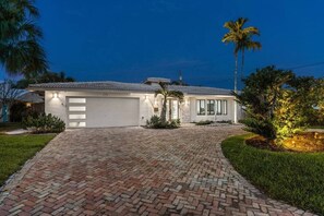 A two-story house with a brick driveway, a garage, and a palm tree. - Heated Pool - Luxury Kitchen - 1 Mile to Beach (Fort Lauderdale)