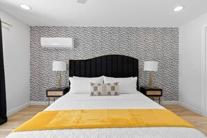 A bedroom with a black headboard, white bedding, two bedside lamps, and a patterned wallpaper. - Heated Pool - Luxury Kitchen - 1 Mile to Beach (Fort Lauderdale)