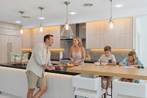 Een moderne keuken met een centraal eiland, hangende lampen en houten kastjes.