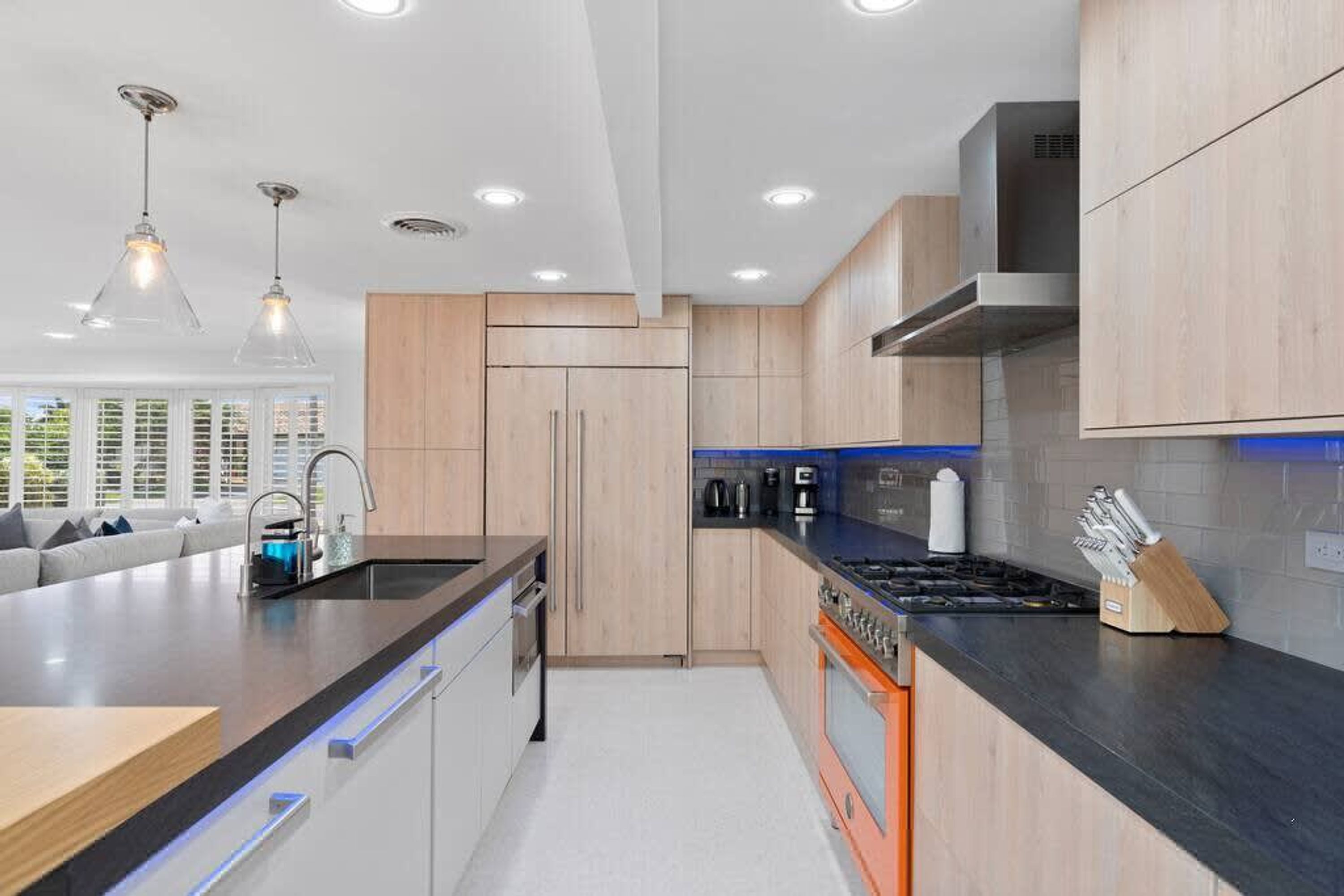 A modern kitchen with wooden cabinets, a central island, and built-in appliances.