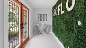 A hallway with a green wall, a white floor, and a door with glass panels. - Heated Pool - Luxury Kitchen - 1 Mile to Beach (Fort Lauderdale)
