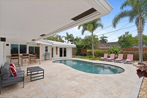 A modern house with a swimming pool, outdoor furniture, and a patio area. - Heated Pool - Luxury Kitchen - 1 Mile to Beach (Fort Lauderdale)