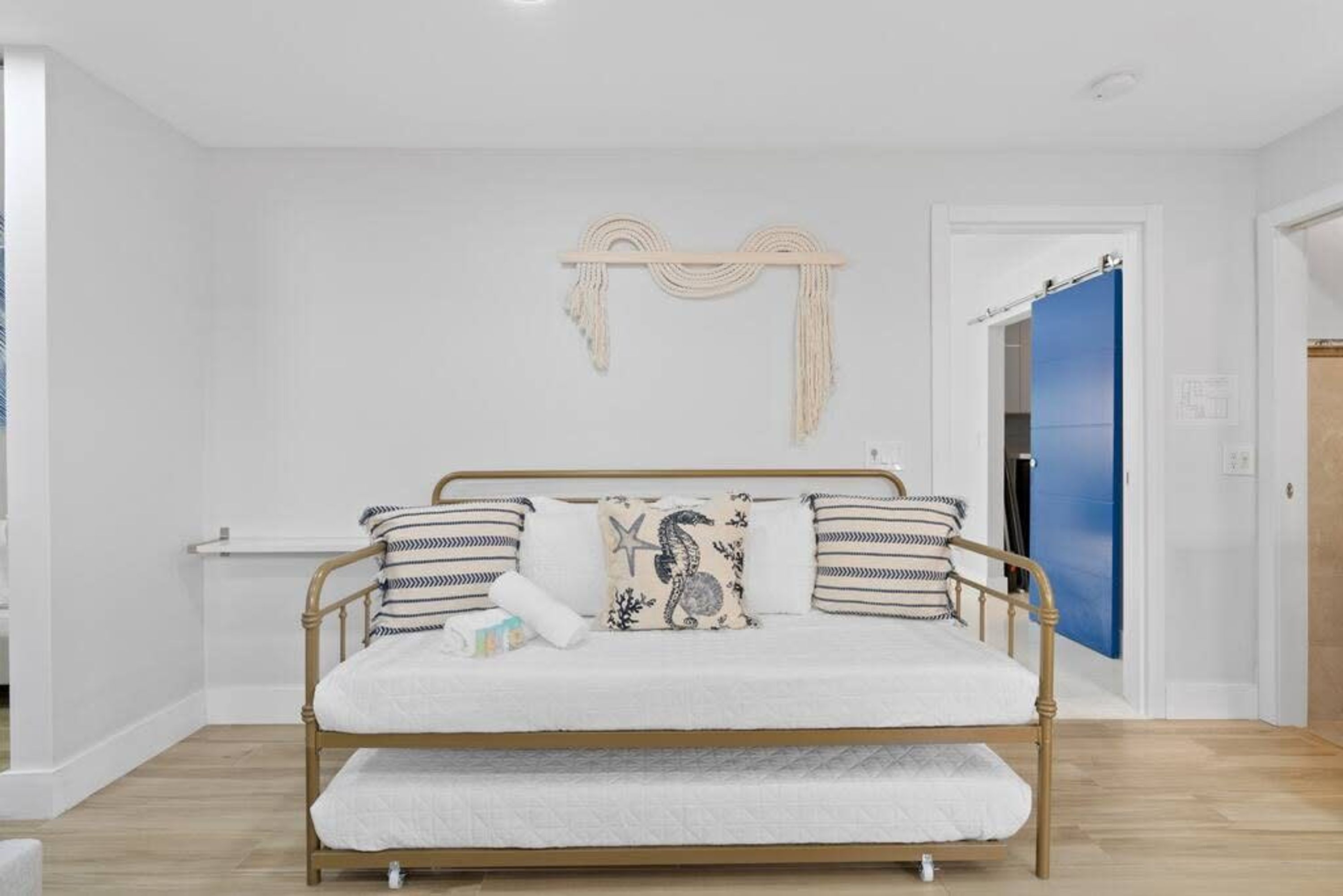 Een bed met houten frame, witte beddengoed en gestreepte kussens.