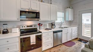 Una cocina moderna con armarios blancos, electrodomésticos de acero inoxidable y piso de madera.