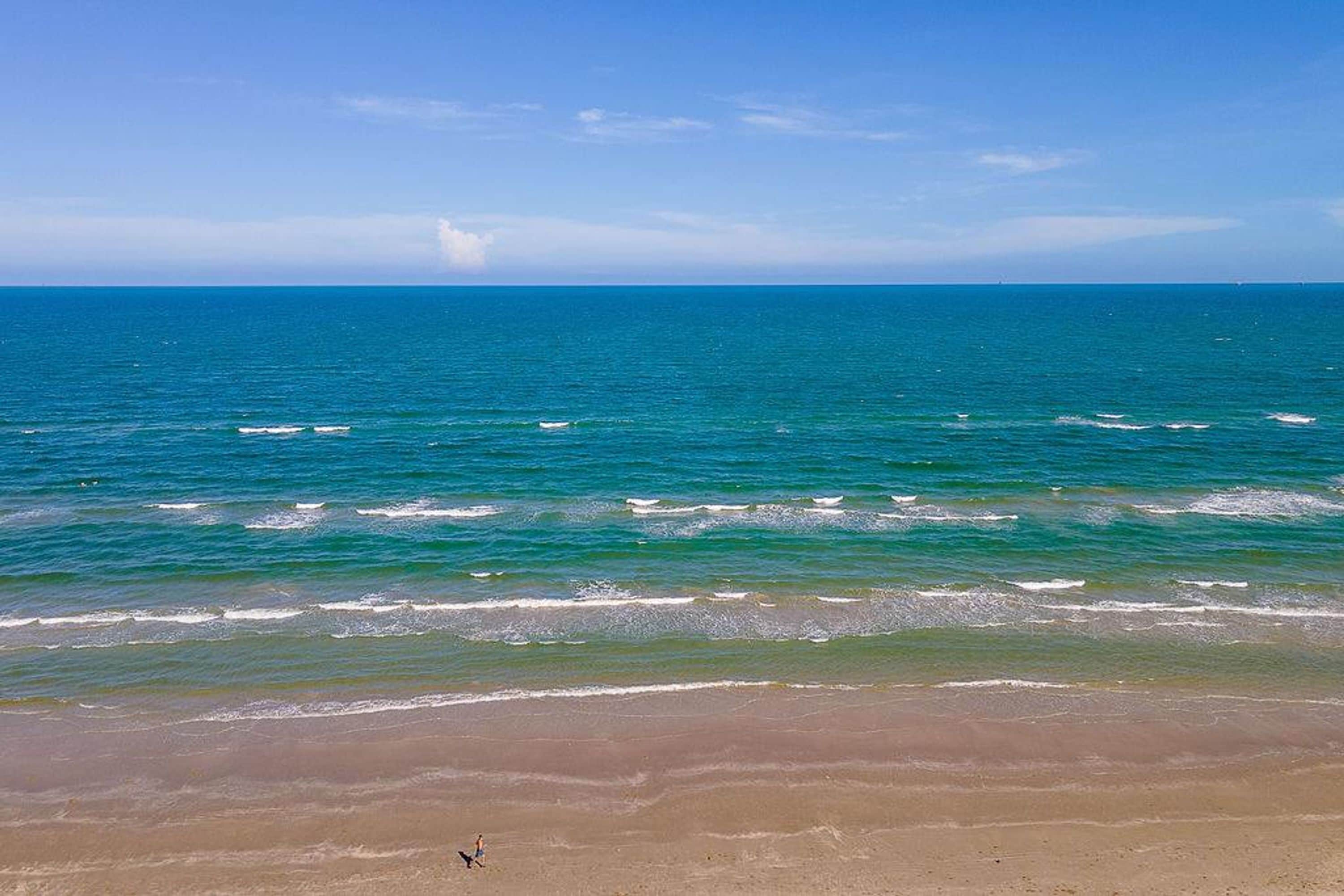 A beach with clear blue water and a sandy shore.
