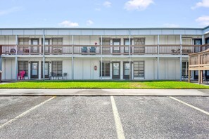 A multi-story building with a flat facade, balconies, and a parking lot in front. - Driftwood Isle Family Friendly Ground Floor (Port Aransas)