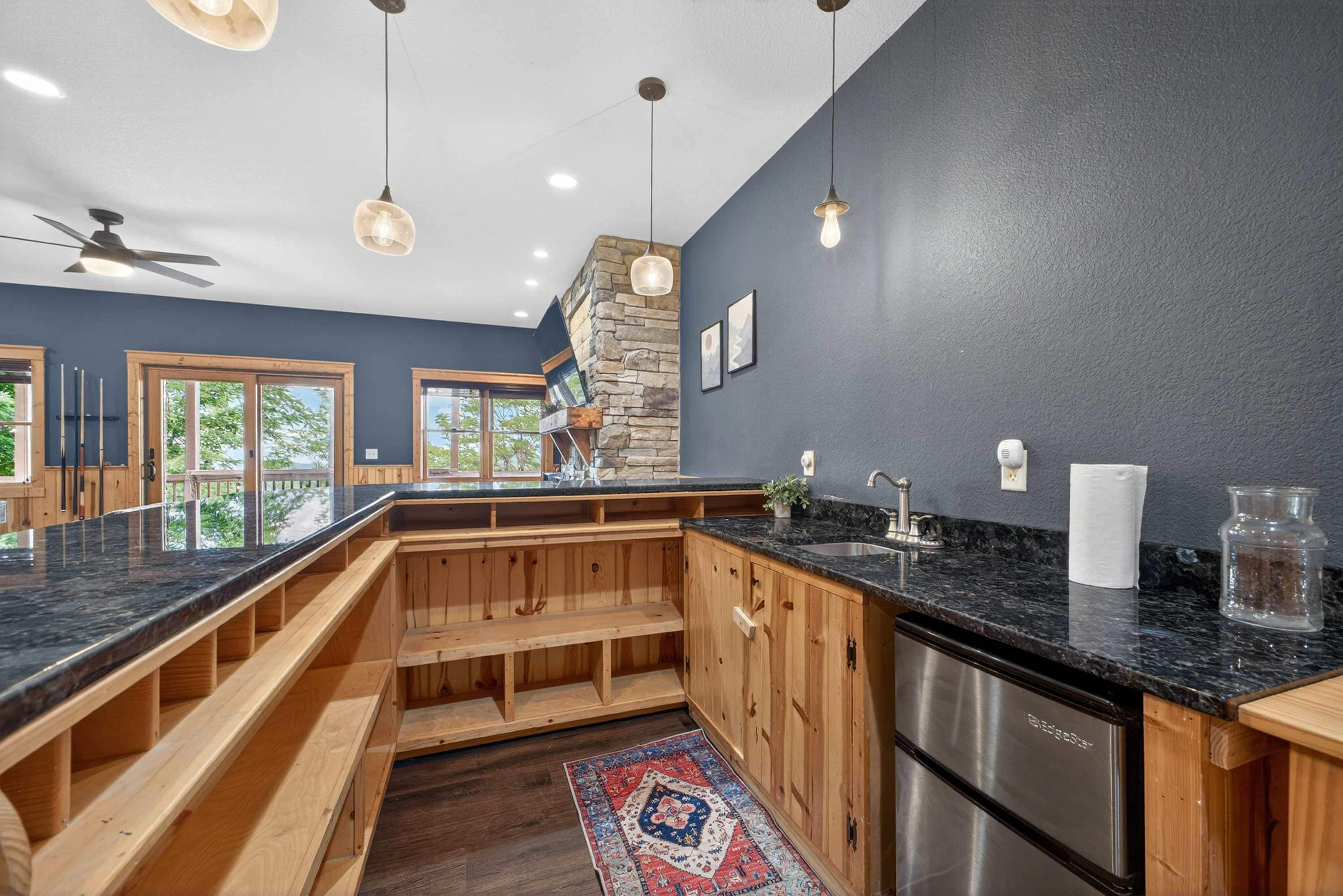 A modern kitchen with a dark wall, wooden cabinets, and a black countertop.
