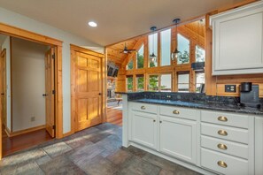 A kitchen with wooden cabinets, a granite countertop, and a view of the outdoors. - Sunset Views for Miles Gameroom Hottub - Fire Pit (Mars Hill)