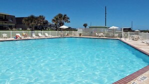 Ein rechteckiger Pool mit weißem Zaun und Liegestühlen darum.