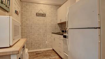 Una cocina compacta con electrodomésticos blancos, encimera de madera y salpicadero de azulejos.
