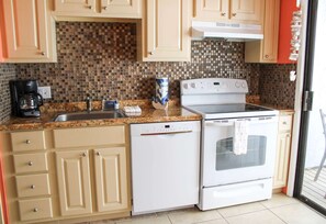 A kitchen with a stove, dishwasher, and coffee maker. - Cozy Canal Retreat Pool Fishing Close to Beach (Corpus Christi)
