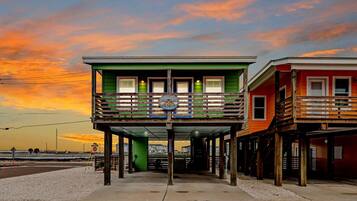 A two-story building with a balcony, a sign, and a view of the beach.
