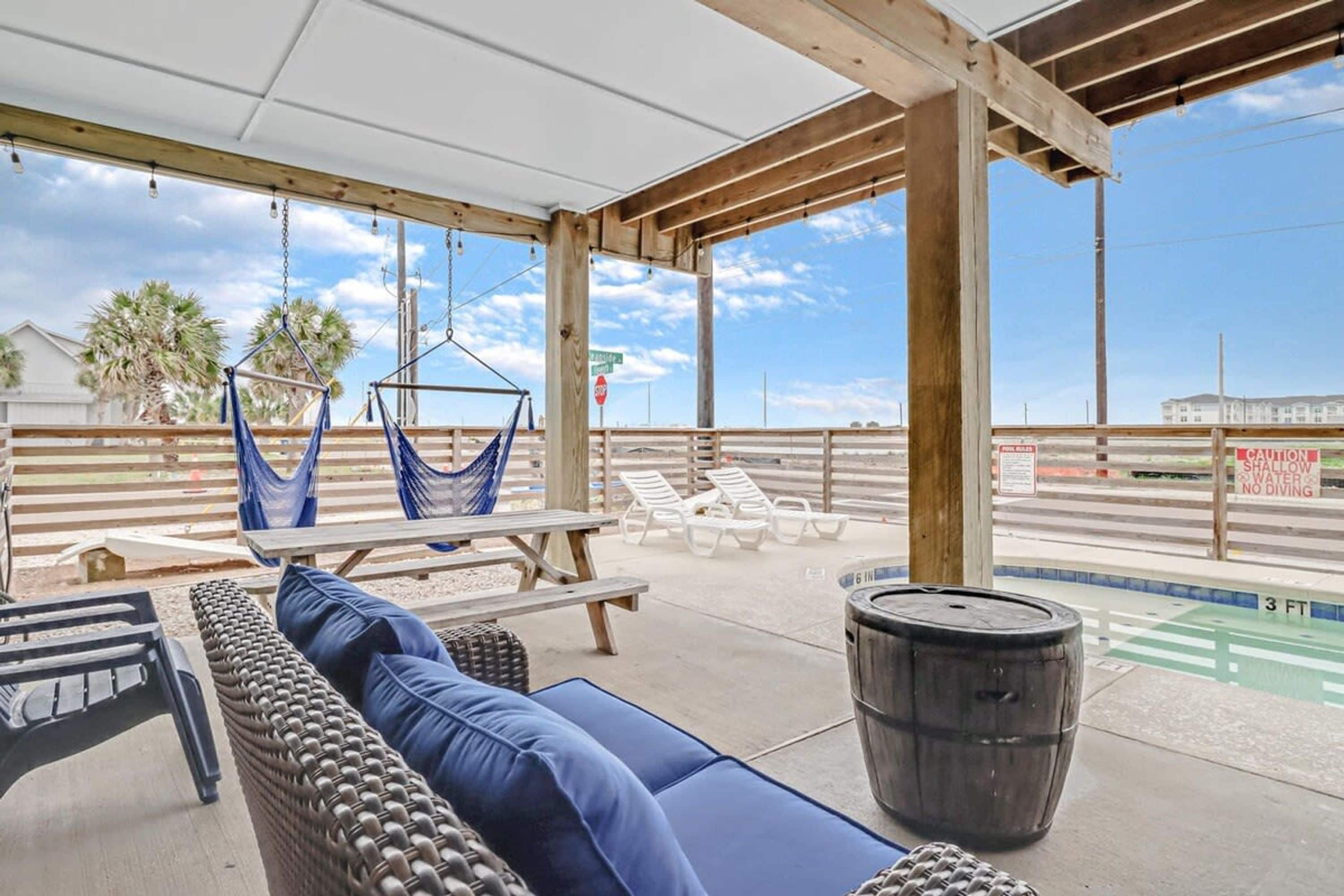 Un espace extérieur aménagé avec une piscine, des chaises longues, un hamac et une pergola en bois.