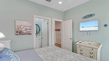 A bedroom with a bed, a dresser, a television, and a door leading to another room.