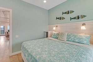 A bedroom with a bed, two wall-mounted lights, and three fish wall art pieces. - Stairway to Seven- Private Pool Hammocks (Port Aransas)