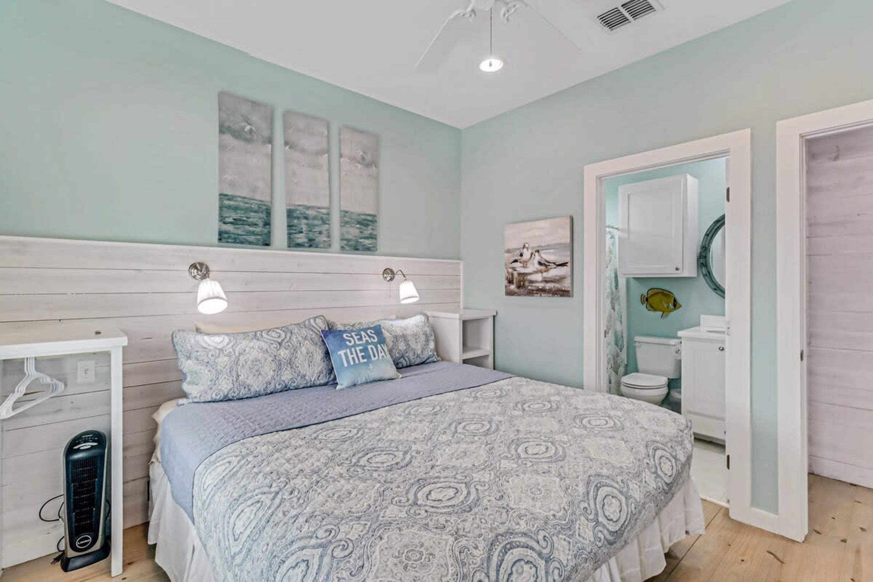 Quarto com cama, mesas de cabeceira, aquecedor, guarda-roupa e banheiro com vaso sanitário e pia.
