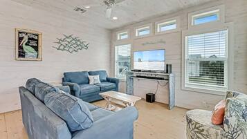 A living room with a blue sofa, a coffee table, and a television on a stand.