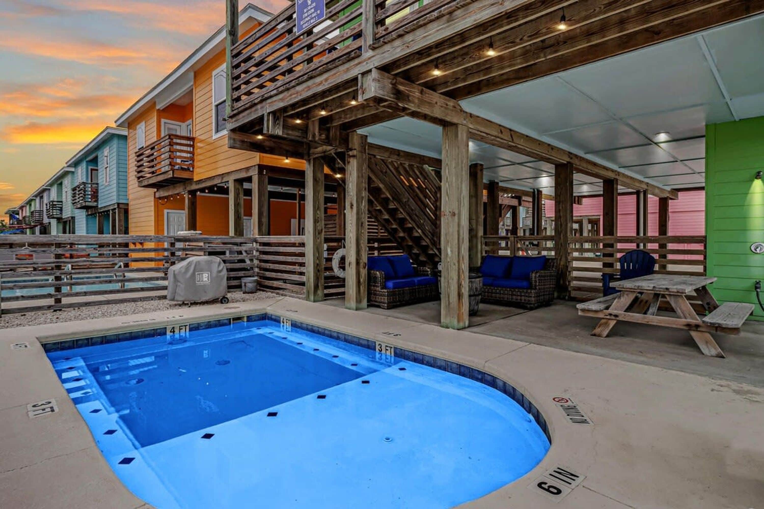 Un espace piscine doté d’un jacuzzi, d’une terrasse en bois et de coins salon extérieurs.