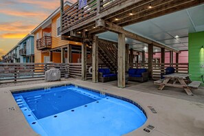 A pool area with a hot tub, wooden deck, and outdoor seating. - Stairway to Seven- Private Pool Hammocks (Port Aransas)