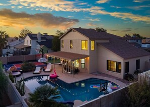 A two-story house with a swimming pool, outdoor seating, and string lights. - Peoria Paradise Basketball Heated Pool Games (Peoria)