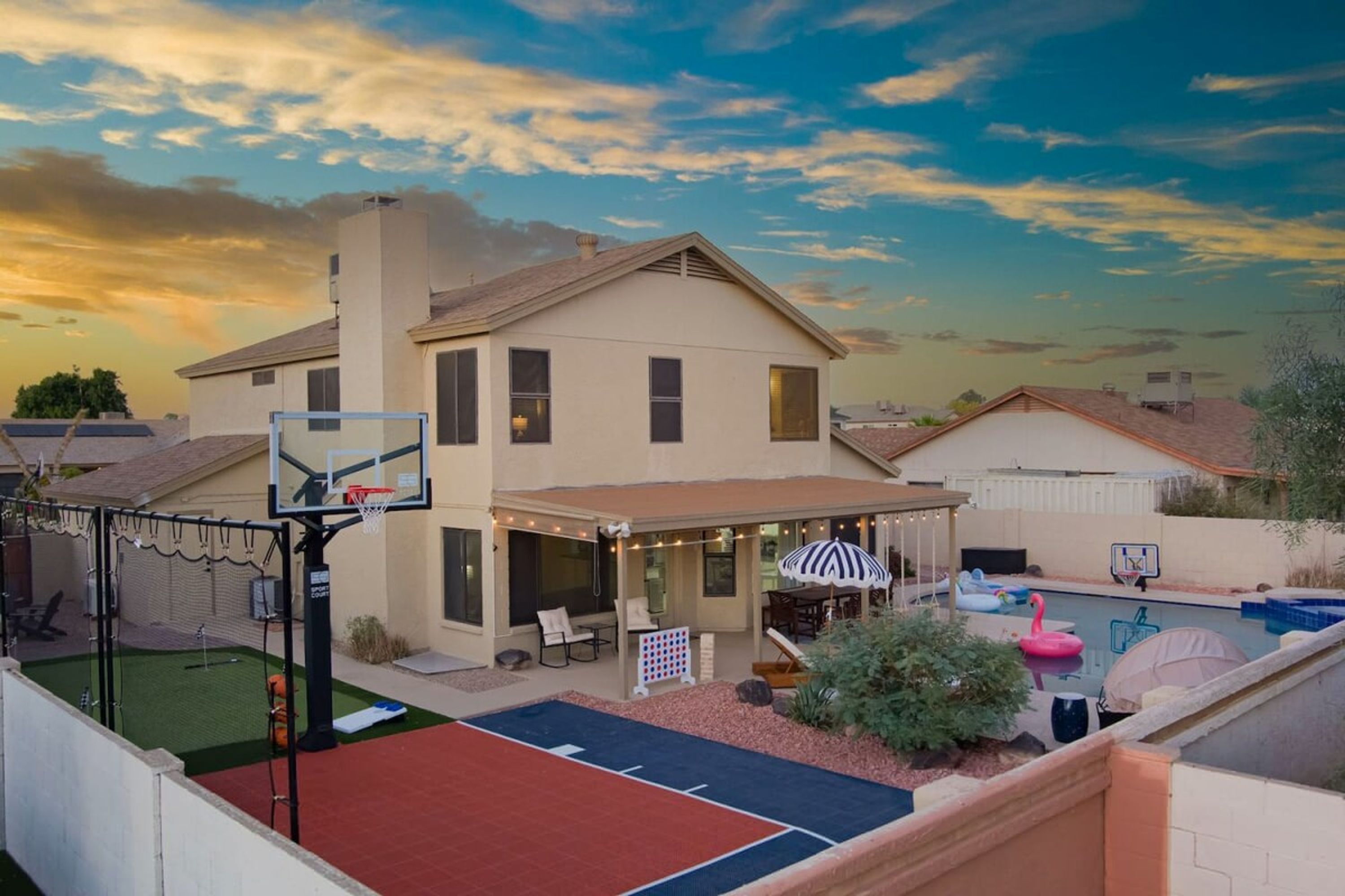 A residential property with a basketball court, outdoor seating area, and a swimming pool.