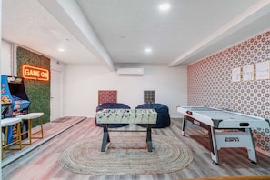 A room with a foosball table, a pool table, and a neon sign reading 'GAME ON'. - Peoria Paradise Basketball Heated Pool Games (Peoria)