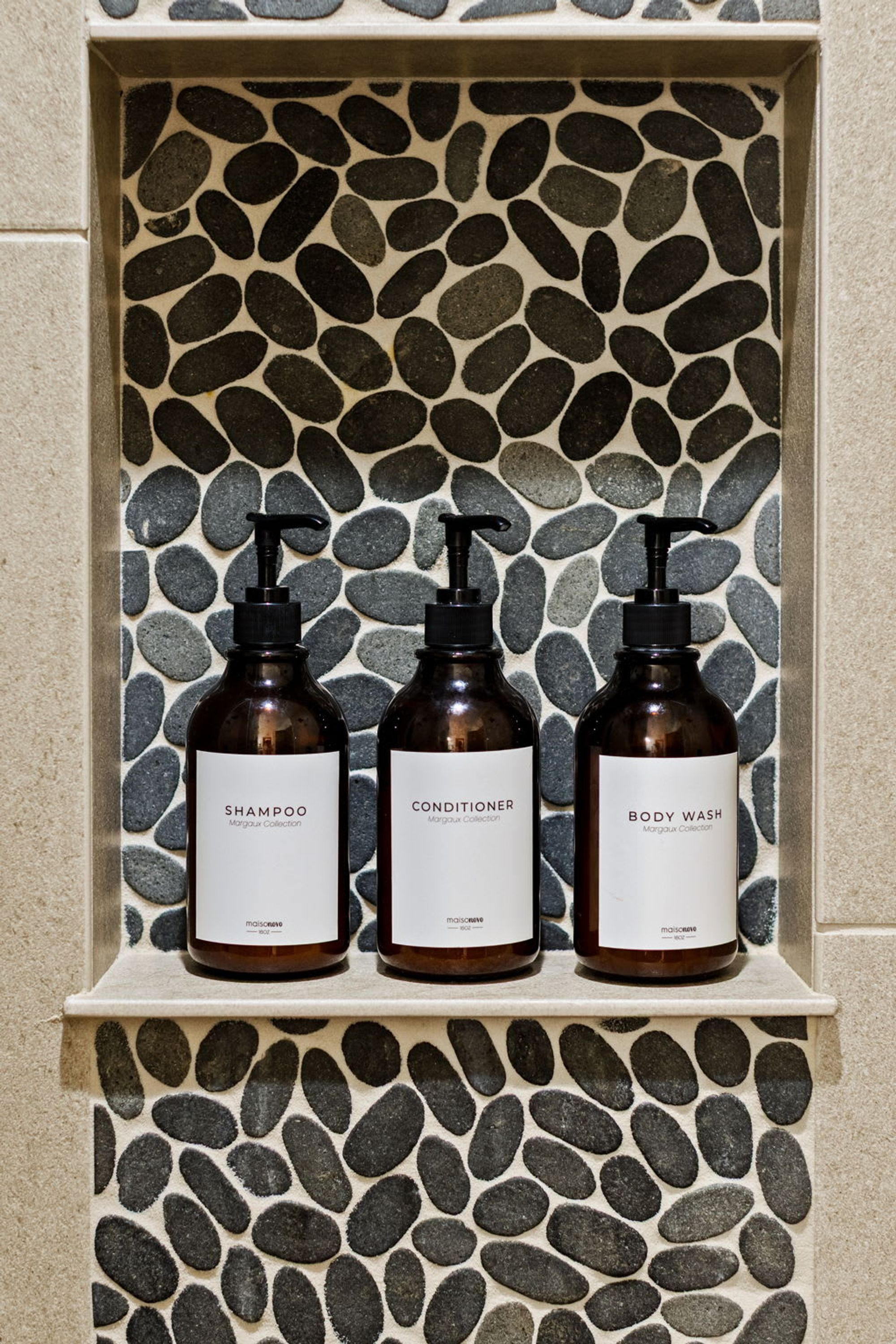 A shelf with three bottles of shampoo, conditioner, and body wash.