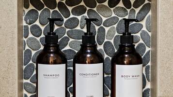 A shelf with three bottles of shampoo, conditioner, and body wash.