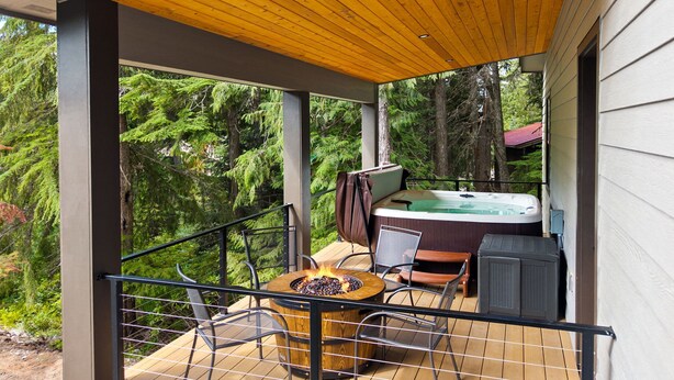 Un balcón con jacuzzi, fogata y mobiliario exterior.