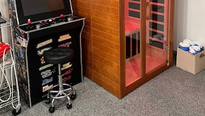 Un salón de juegos con una máquina 'Legends Ultimate', una sauna y un armario.