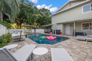 A backyard with a swimming pool, lounge chairs, and a covered patio area. - Hot Tub Sportscourt Game Room 5 min to Beach (Seminole)