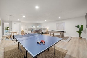 Ein geräumiger Raum mit Tischtennisplatte, Kicker und Stockbetten.