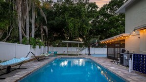 A swimming pool with a white fence, a hammock, and a covered seating area. - Hot Tub Sportscourt Game Room 5 min to Beach (Seminole)
