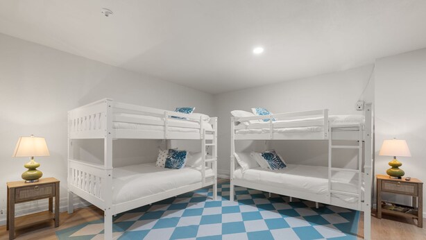 A room with two bunk beds, a checkered floor, and two bedside tables with lamps. - Hot Tub Sportscourt Game Room 5 min to Beach (Seminole)