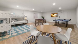 A room with bunk beds, a foosball table, a ping pong table, and a round table with chairs. - Hot Tub Sportscourt Game Room 5 min to Beach (Seminole)